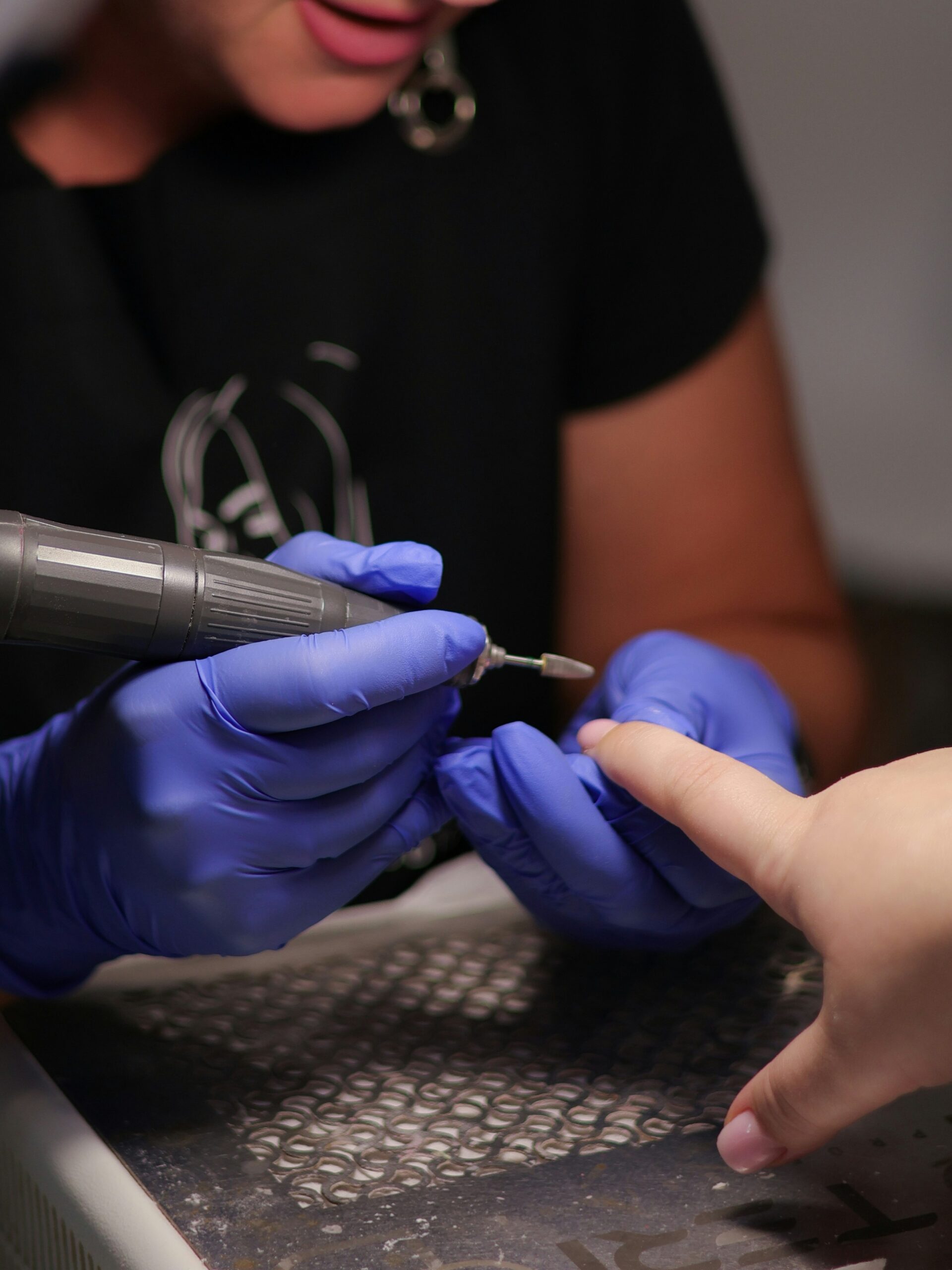 nail tech using e-file in salon to remove BIAB manicure