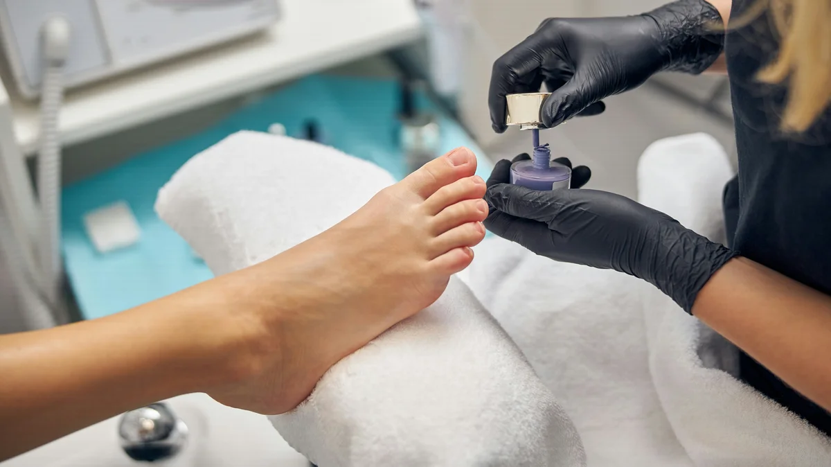 Close-up of a technician giving a client a pedicure in salon