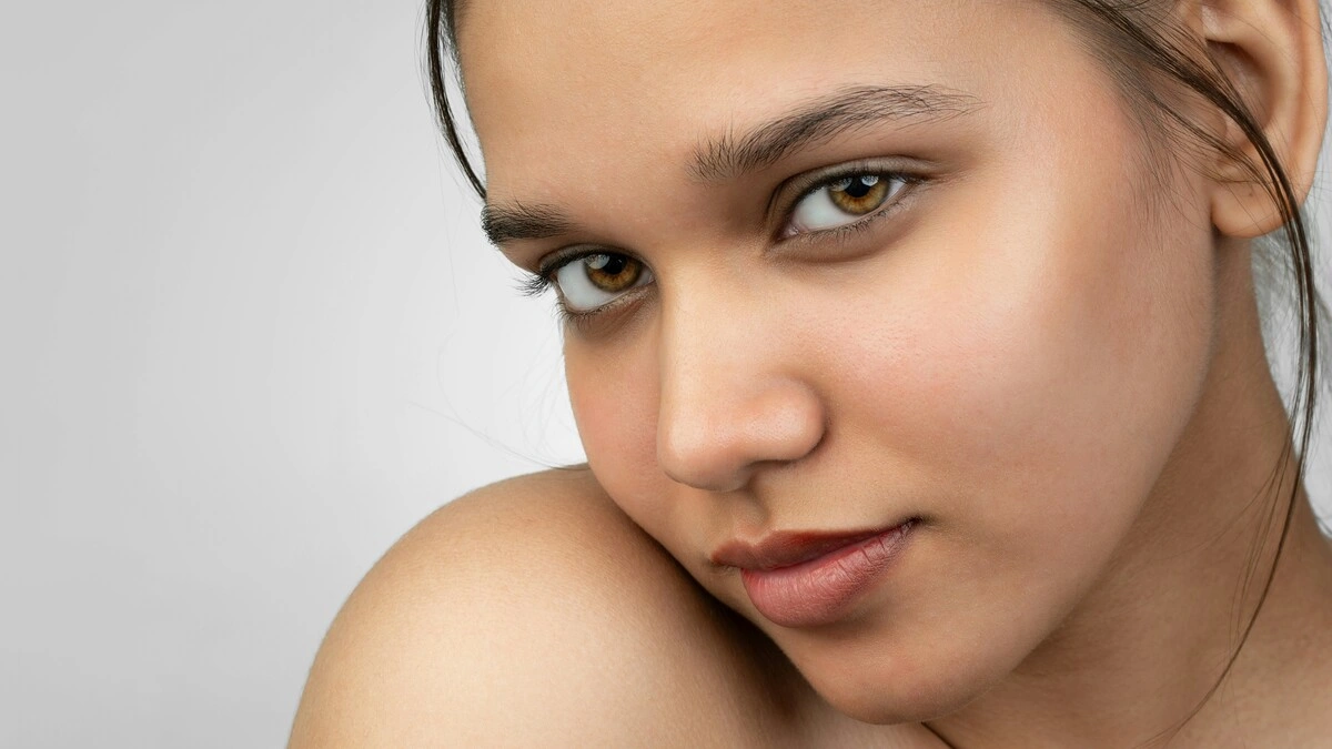Close-up of a woman smiling to the camera showing her make-up free smooth skin