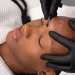 Close-up of an aesthetician performing dermaplaning on a client in salon