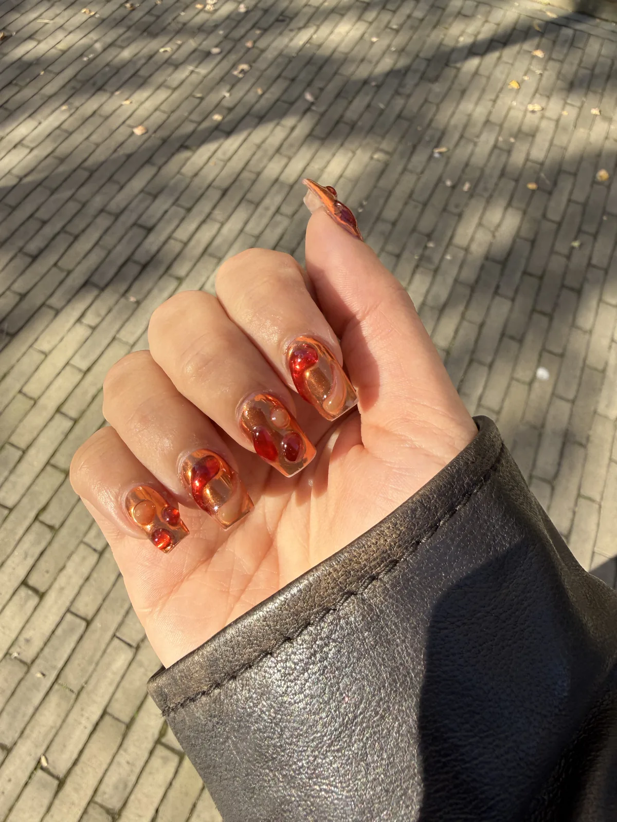 Lava nail art with amber and red swirls on a sheer base