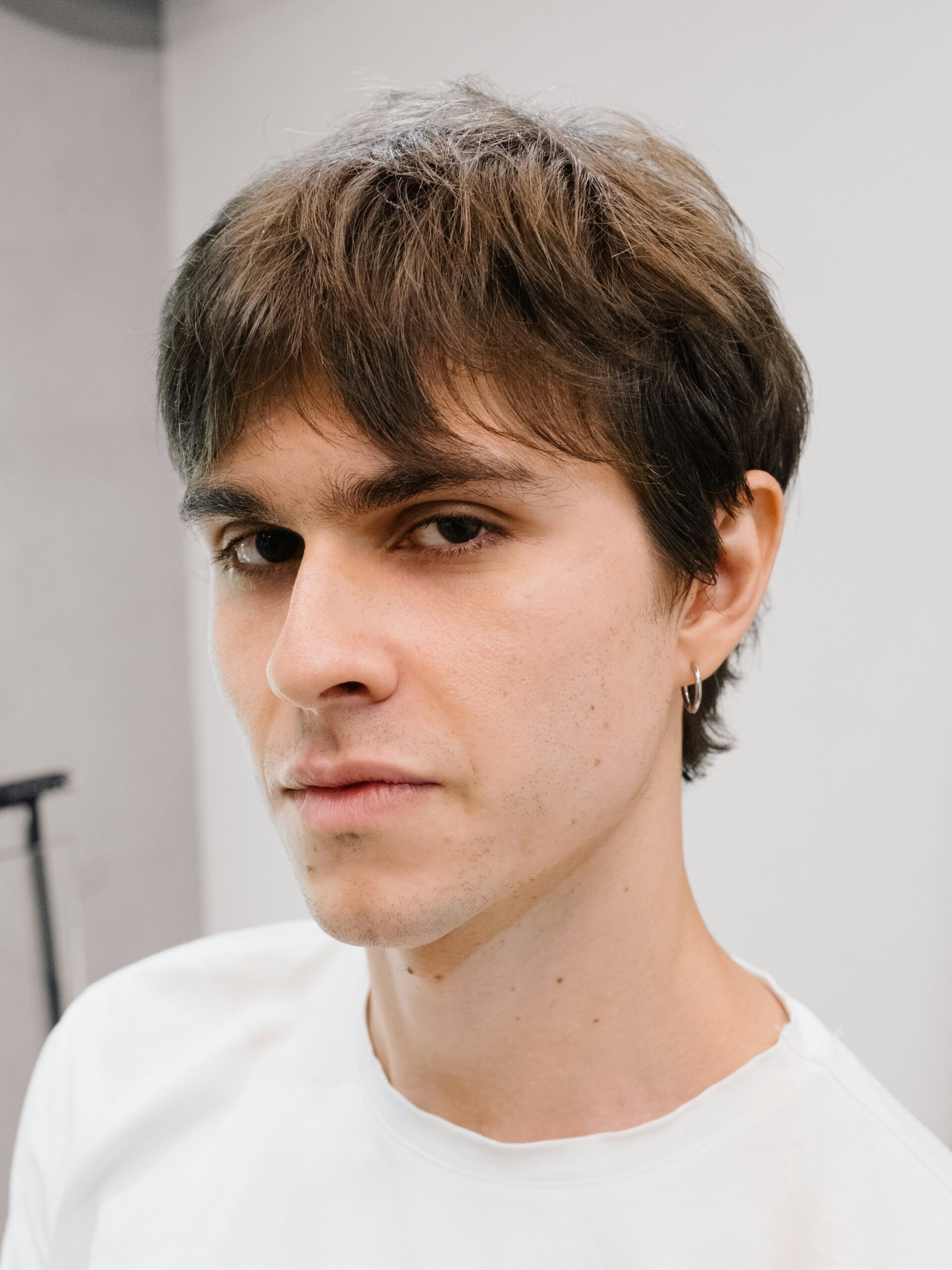 Un jeune homme avec un mulet sobre, portant un t-shirt blanc.