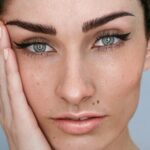 Gros plan sur le visage d’une femme avec un microblading des sourcils, un maquillage naturel et les cheveux bruns attachés