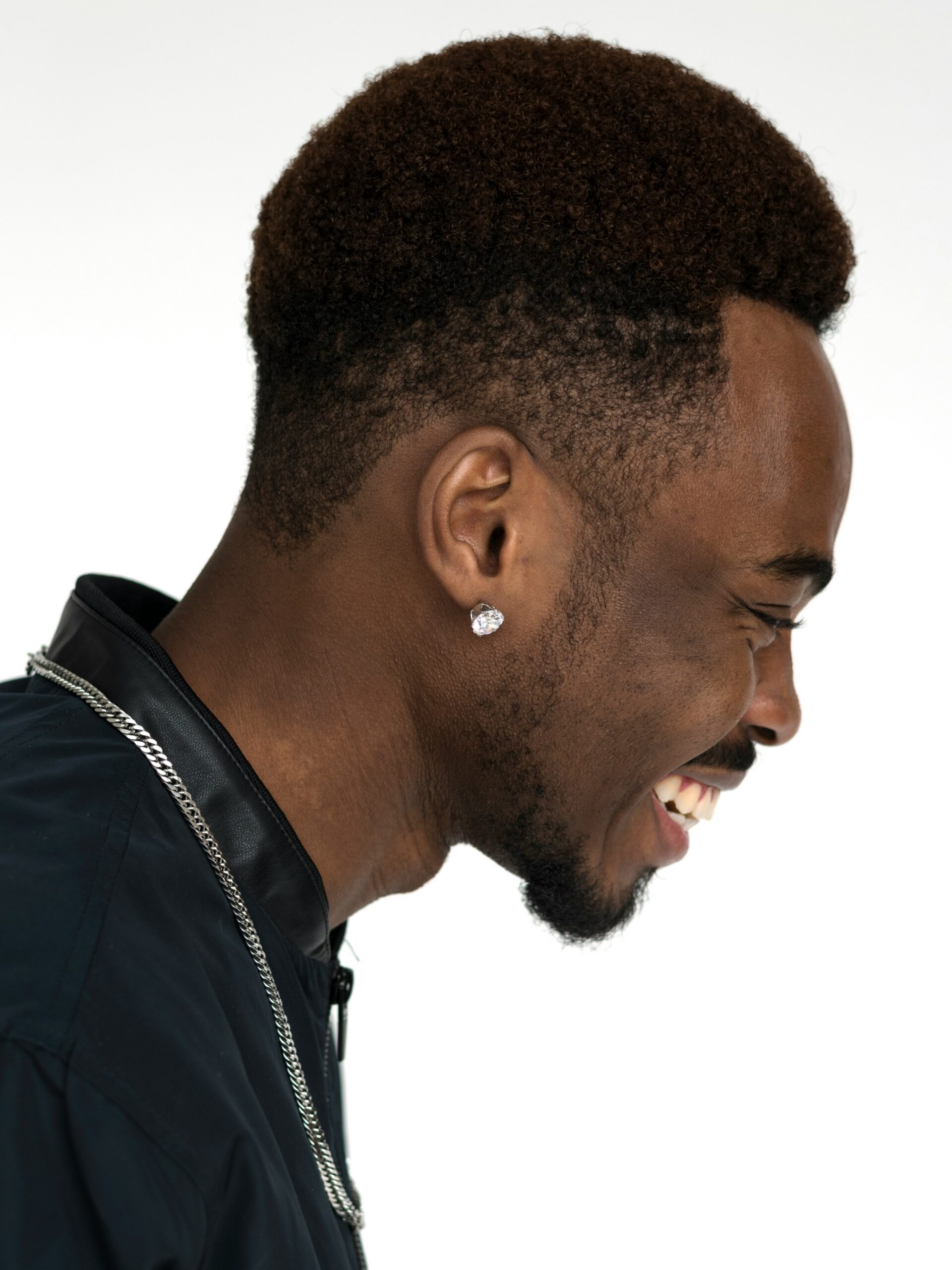 Profil d'un homme souriant avec des cheveux afro associés à un taper fade haut