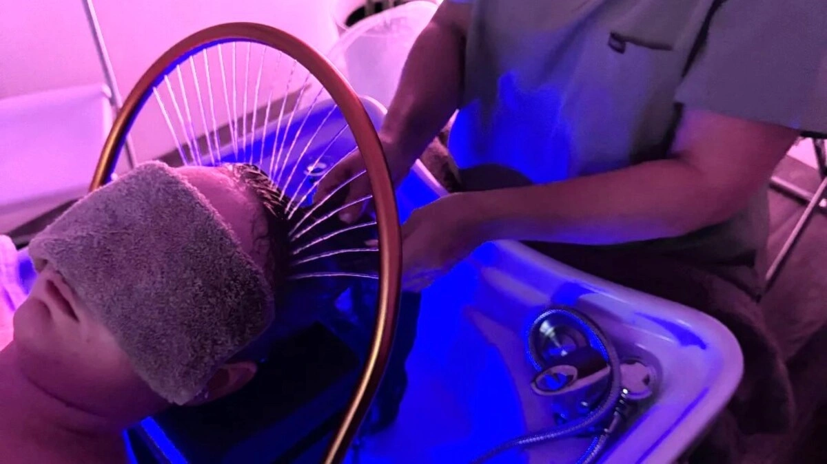 Vue de dessus d'un praticien lavant les cheveux d'une cliente pendant un head spa japonais