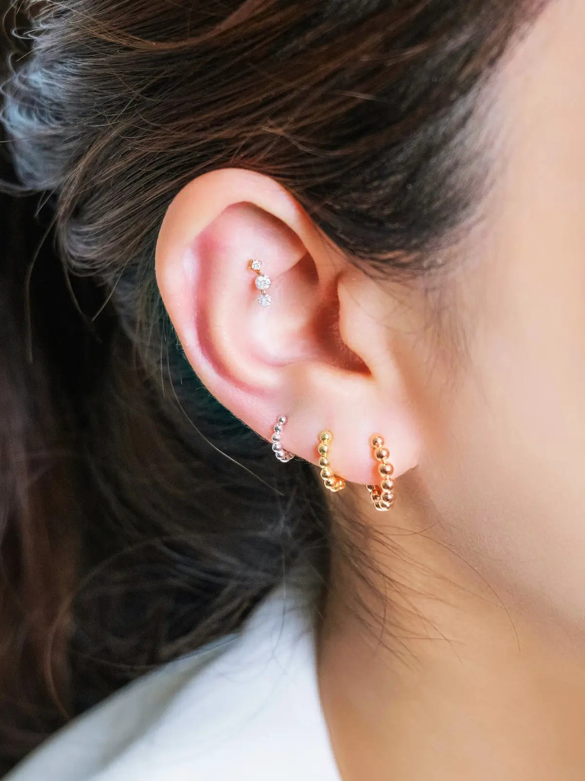 Gros plan sur l'oreille d'une femme portant plusieurs anneaux et un clou d'hélix