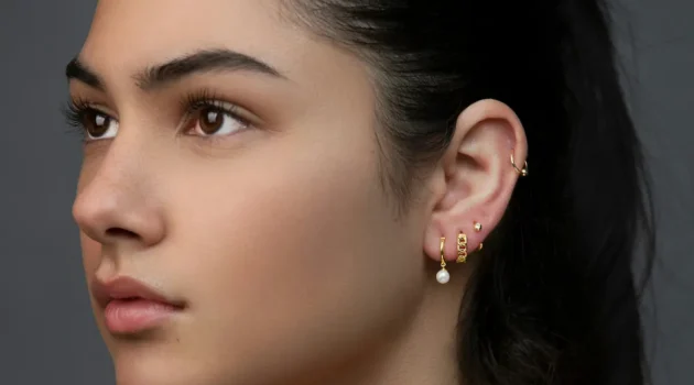 Photo en studio d'une femme arborant un curated ear avec plusieurs piercings au lobe et un anneau d'hélix