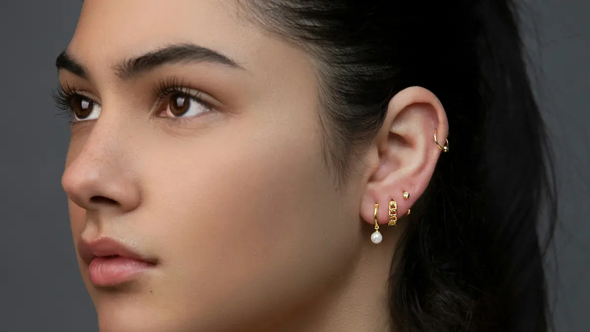 Photo en studio d'une femme arborant un curated ear avec plusieurs piercings au lobe et un anneau d'hélix