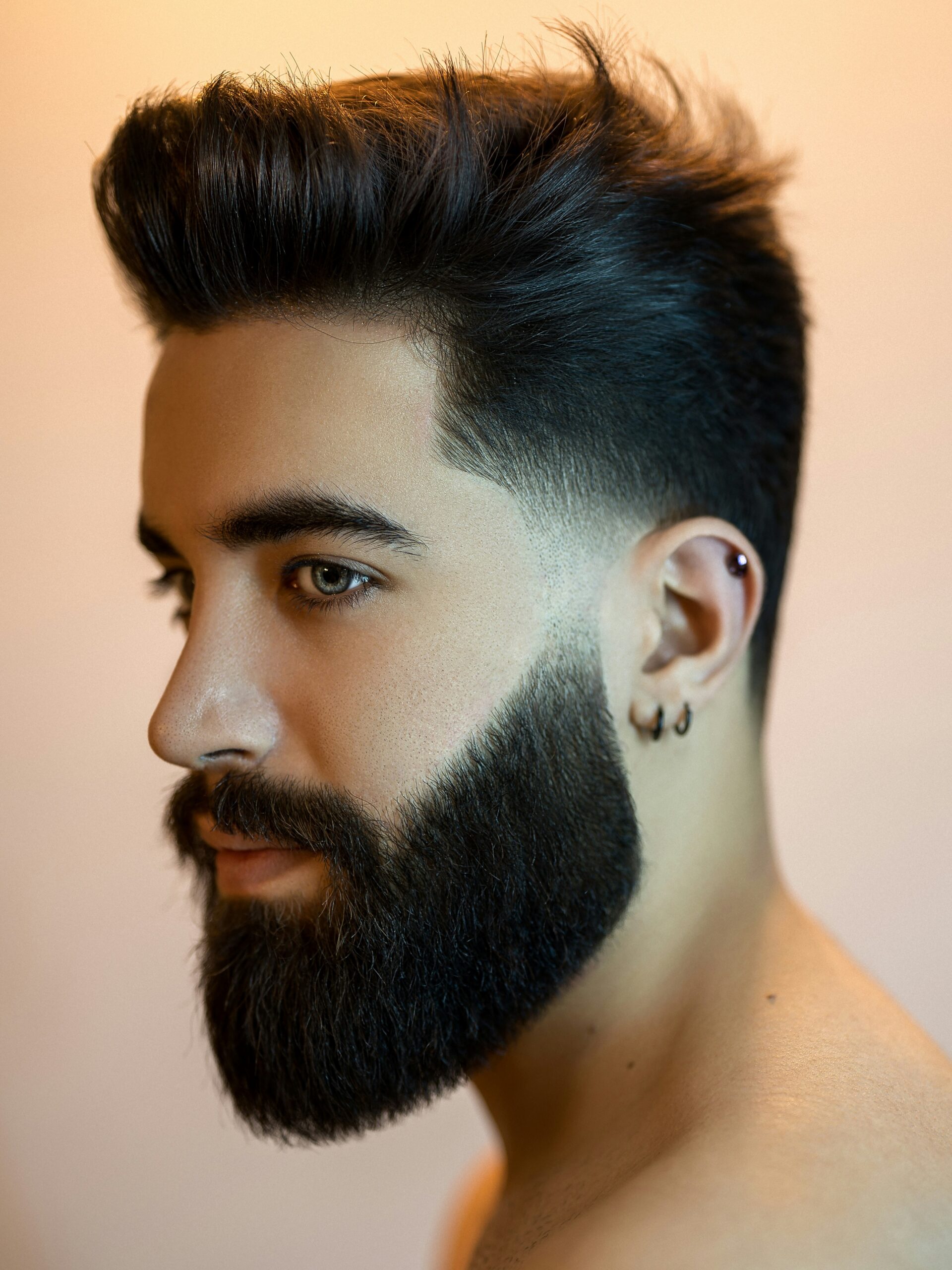 Man met een ovaal gezicht en donker haar met een low taper fade met volume en een baard