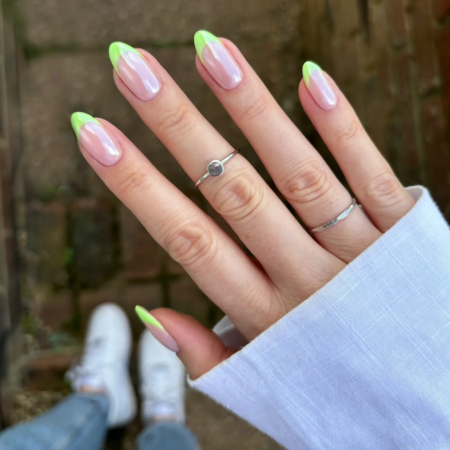 Amandelnagels met limoengroene Franse tips over een glazed, parelmoerachtige chrome-basis.