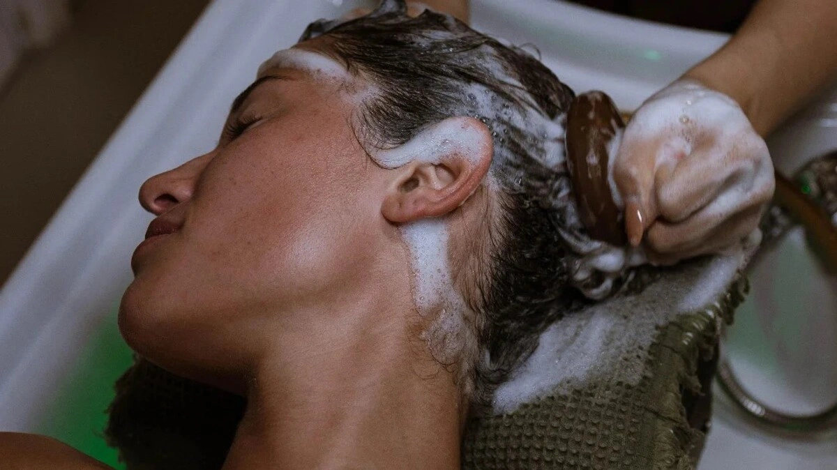 Close-up van een behandelaar die een Japanese head spa uitvoert met een hoofdhuidborstel bij een klant