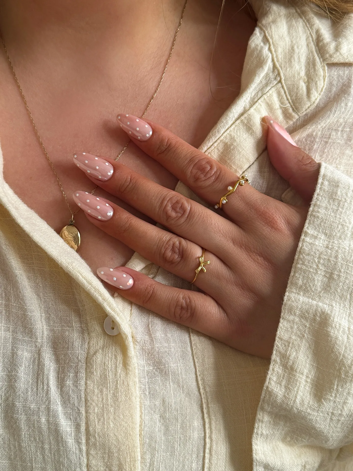 Amandelnagels in een transparante roze basis, bezaaid met gelijkmatig geplaatste witte micro polka dots.