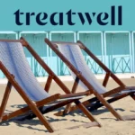Twee gestreepte houten ligstoelen op het zand voor pastelblauwe strandhuisjes aan de kust van Versilia