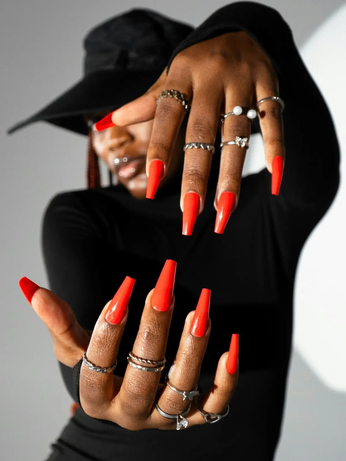 Een vrouw houdt haar verzorgde handen voor de camera en laat feloranje coffinvormige acrylnagels zien