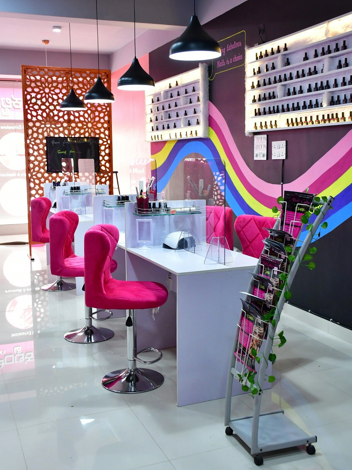Interieur van een nagelsalon met schone, opgeruimde witte balies, roze velours stoelen en een paarse muur