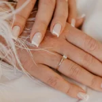 Klassieke witte French manicure op natuurlijke, vierkant gevijlde nagels op een witte stof