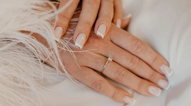 Klassieke witte French manicure op natuurlijke, vierkant gevijlde nagels op een witte stof