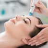 Close-up van een ontspannen vrouw met gesloten ogen tijdens een HydraFacial-behandeling in een rustige salon