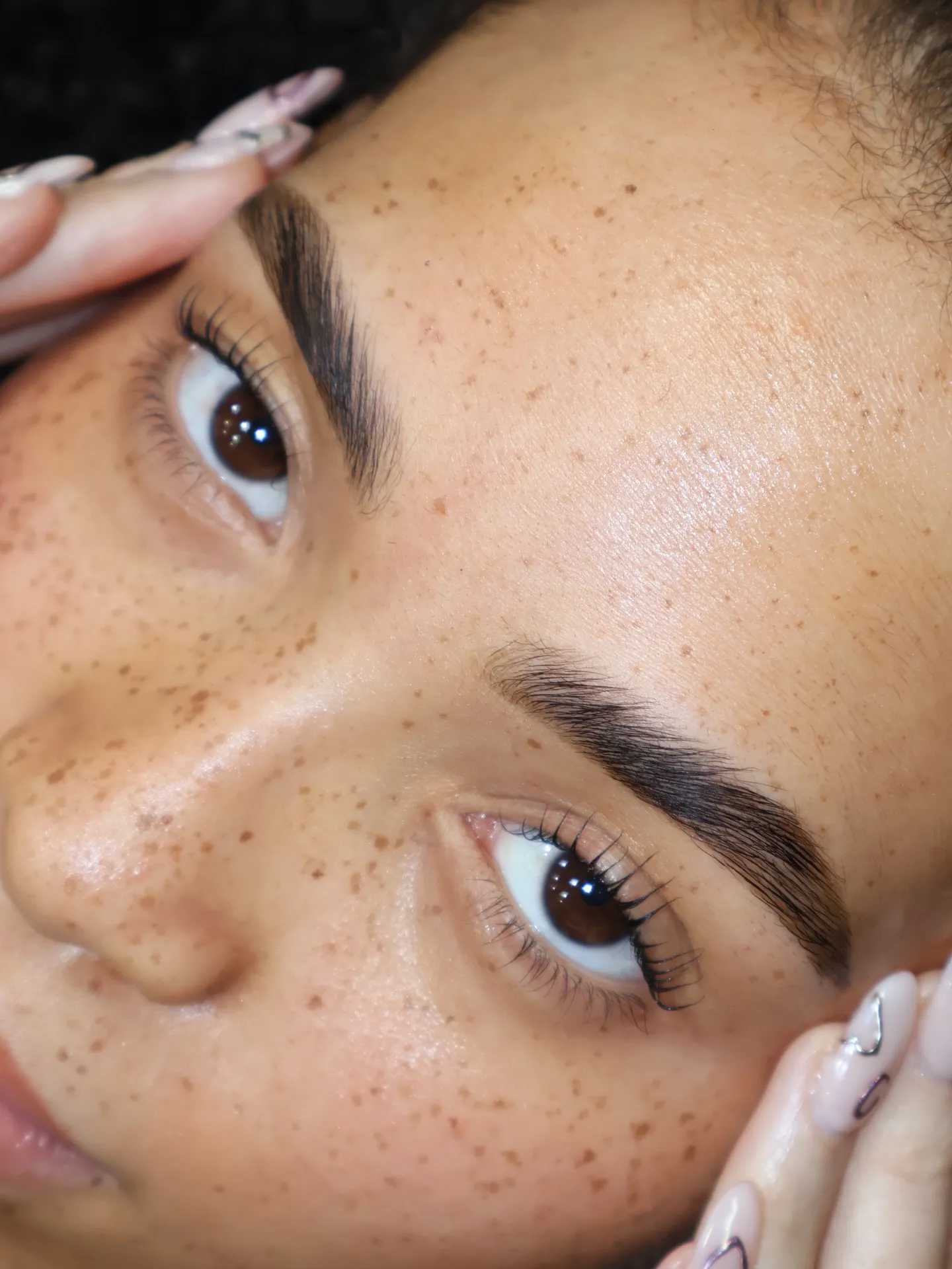 Close-up van natuurlijk gelifte wimpers na een Korean lash lift, zachte, mooi gescheiden krul met luchtige structuur op een huid met sproeten