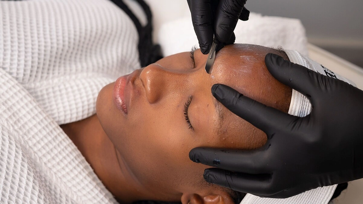 Close-up van een schoonheidsspecialist die dermaplaning uitvoert bij een klant in een salon