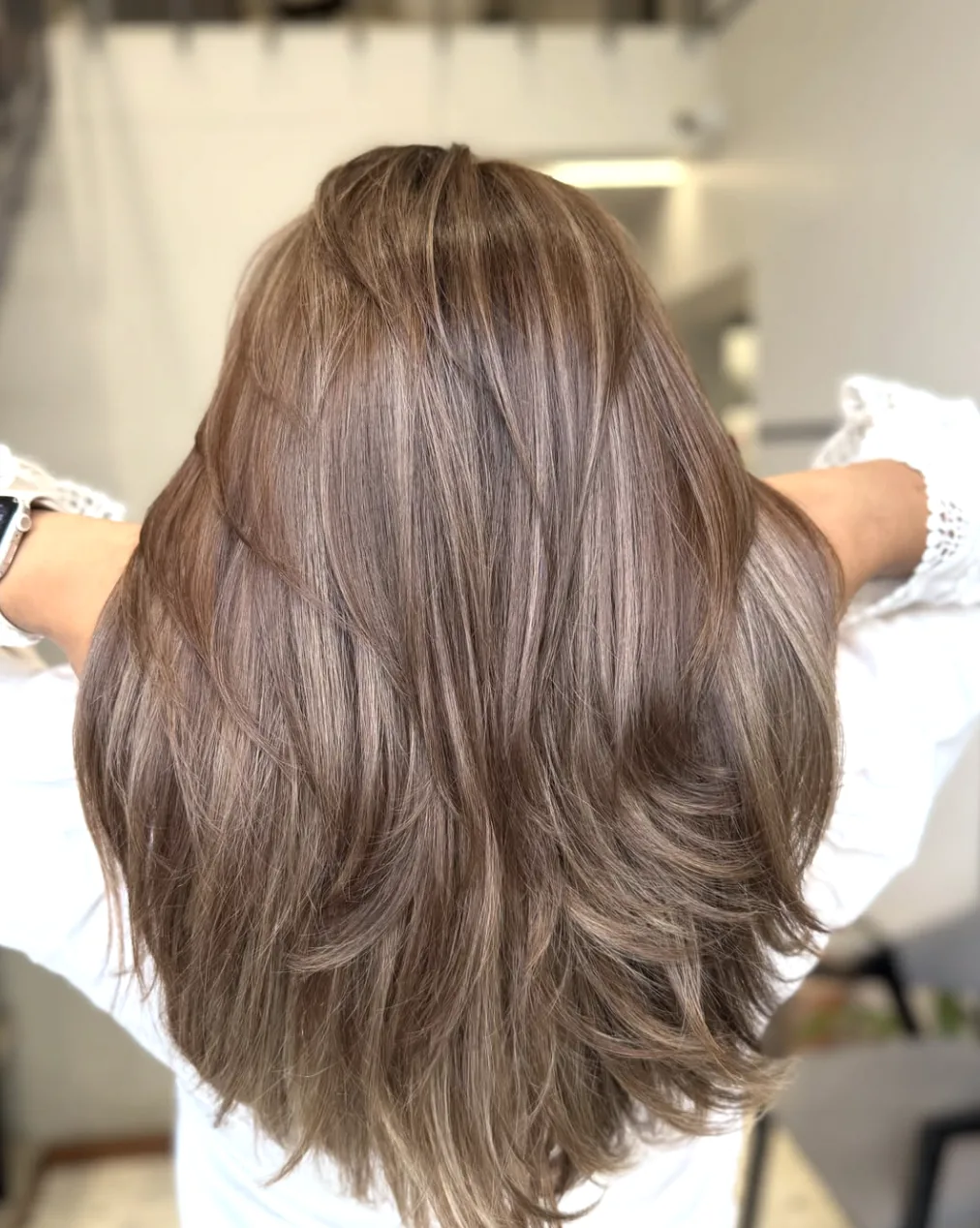 Lang, gelaagd haar in een meertonige taupe truffle-brunette tint